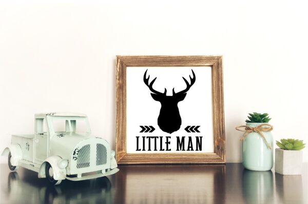 A small toy truck, a 12x12Little Man framed sign with a deer head silhouette, and two potted succulents are arranged on a white surface against a plain wall. - Spruced Studio Upscale Workshop