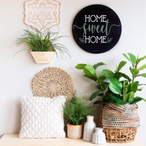 A decorative display featuring potted plants, woven baskets, vases, a textured pillow, and the "Home Sweet Home 2" round sign on a light-colored wall. - Spruced Studio Upscale Workshop