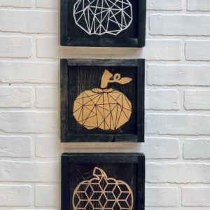 The 9x9 Geometric Pumpkins artwork features three framed geometric pumpkin designs in white, orange, and brown, vertically stacked on a white brick wall. - Spruced Studio Upscale Workshop