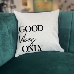 A "Good Vibes Only" white pillow rests on a green velvet couch in a modern living room. - Spruced Studio Upscale Workshop