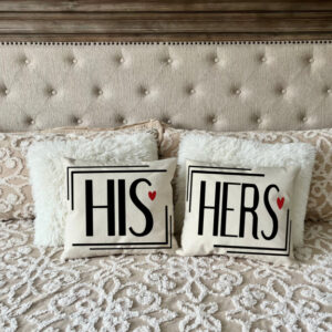 The His + Hers bed features a tufted headboard, decorative pillows, and two accent pillows labeled "HIS" and "HERS" with small red hearts. - Spruced Studio Upscale Workshop