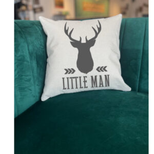 The "Little Man" throw pillow features a black deer head silhouette and text, shown on a green velvet couch. - Spruced Studio Upscale Workshop