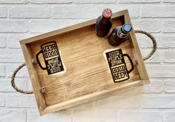 The Tray w/ Sides - Good People Good Beer includes a wooden tray with rope handles, two beer bottles, and two coasters featuring the phrase "GOOD PEOPLE DRINK GOOD BEER" in black text on white. - Spruced Studio Upscale Workshop