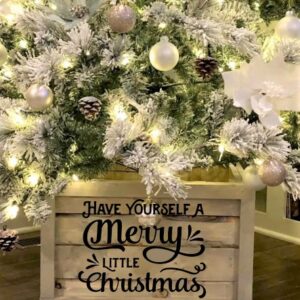 A Christmas tree with white ornaments and lights stands on the Tree Box - Have Yourself a Merry Christmas, which features the festive message on its side. - Spruced Studio Upscale Workshop