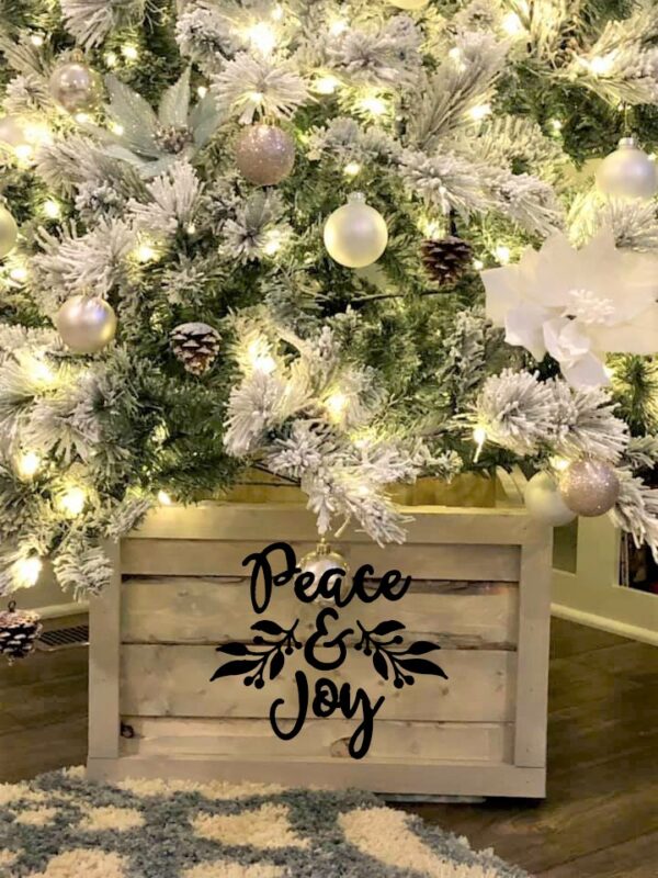 A Christmas tree with white and silver ornaments sits in the Tree Box - Peace & Joy, surrounded by warm lights. - Spruced Studio Upscale Workshop