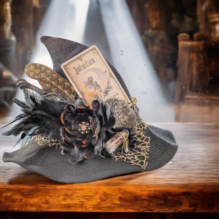 A pointed black witch hat decorated with feathers, a black flower, a tarot card labeled "Intuition," lace, and a small vial, resting on a wooden surface with light beams in the background. - Spruced Studio Upscale Workshop