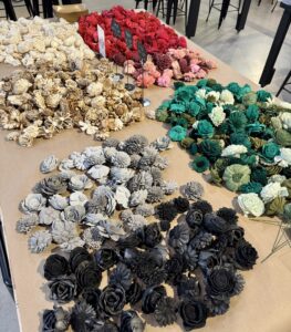 Assorted artificial flowers in various colors, including white, red, pink, green, gray, and black, are arranged in groups on a table indoors. - Spruced Studio Upscale Workshop