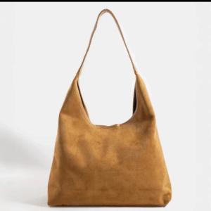 A tan suede shoulder bag with a single strap, displayed against a plain white background. - Spruced Studio Upscale Workshop