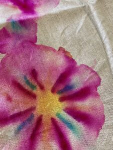 Close-up of a fabric with a tie-dye floral pattern in pink, yellow, blue, and purple hues on a beige background. - Spruced Studio Upscale Workshop