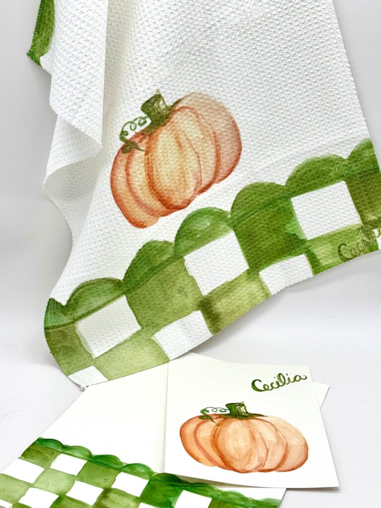 White towel and card with green checkered border and orange pumpkin illustration, displayed on a white surface. - Spruced Studio Upscale Workshop